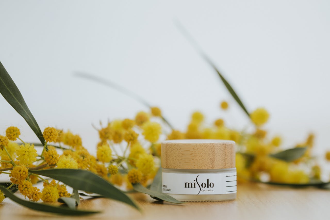 Close-up of a natural face cream jar surrounded by yellow flowers in a studio setting, ideal for skincare themes.