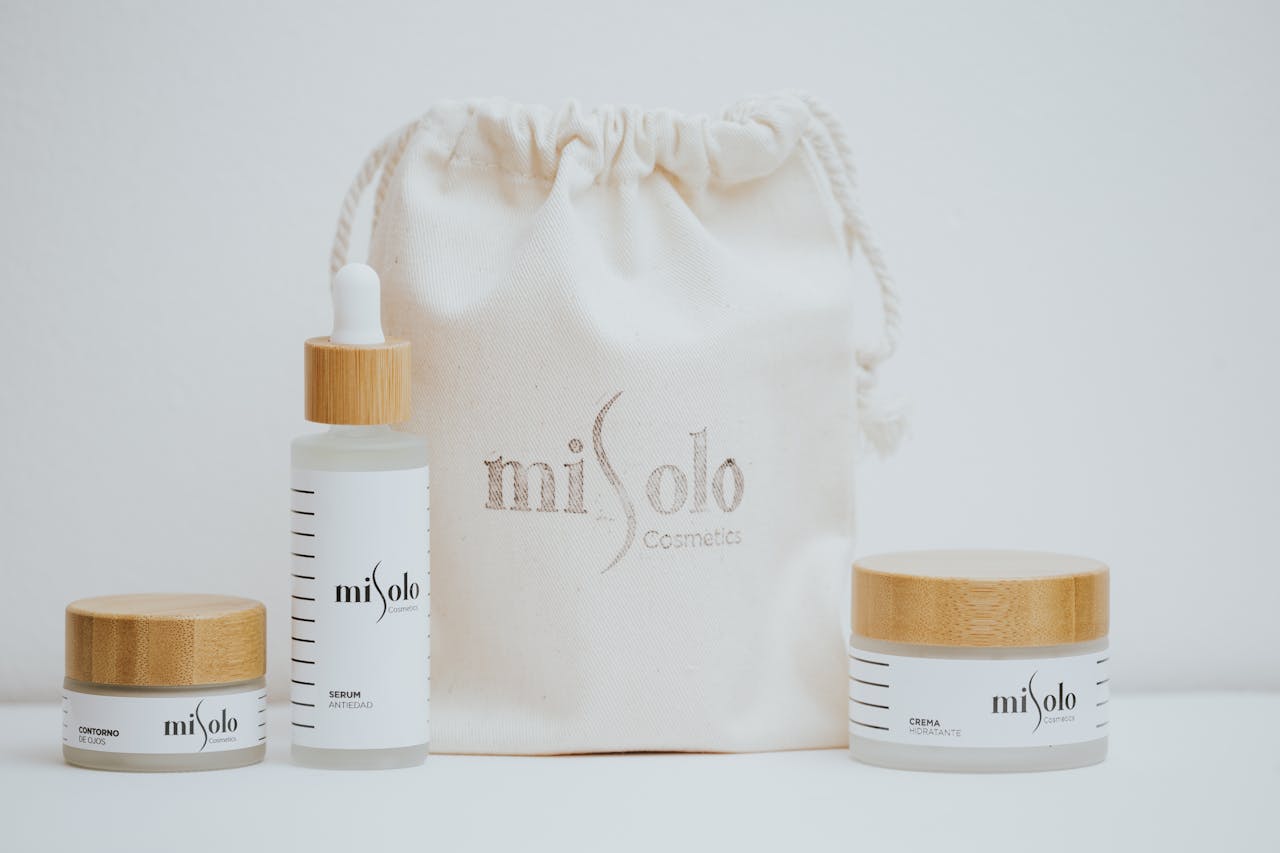 Minimalist photo of organic skincare products with bamboo lids and a canvas bag on a white background.